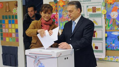 Der ungarische Regierungschef Viktor Orban und seine Frau Aniko Levai werfen ihre Stimmzettel in eine weiße Urne