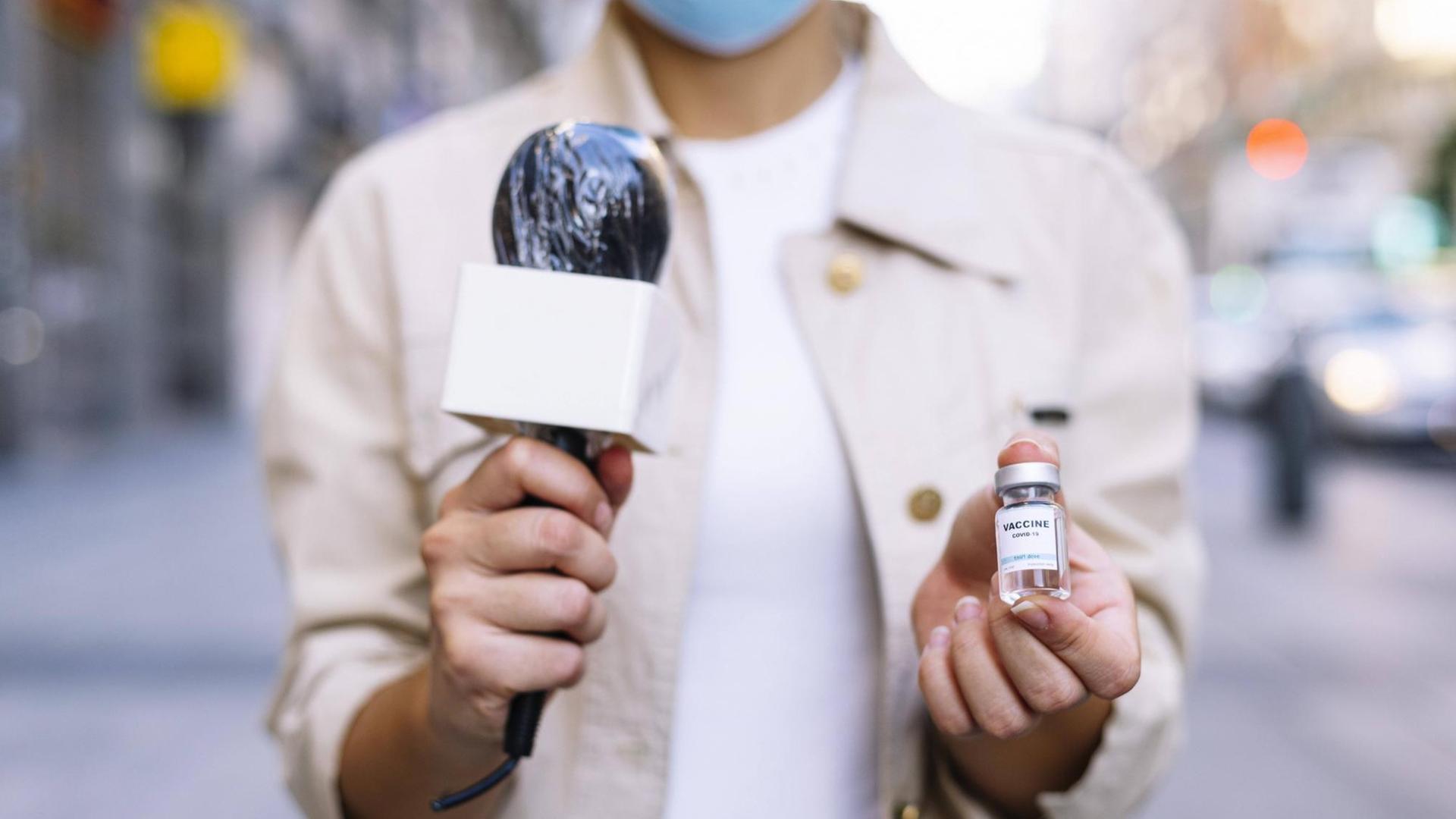Eine Reporterin hält eine Impfdosis in die Kamera