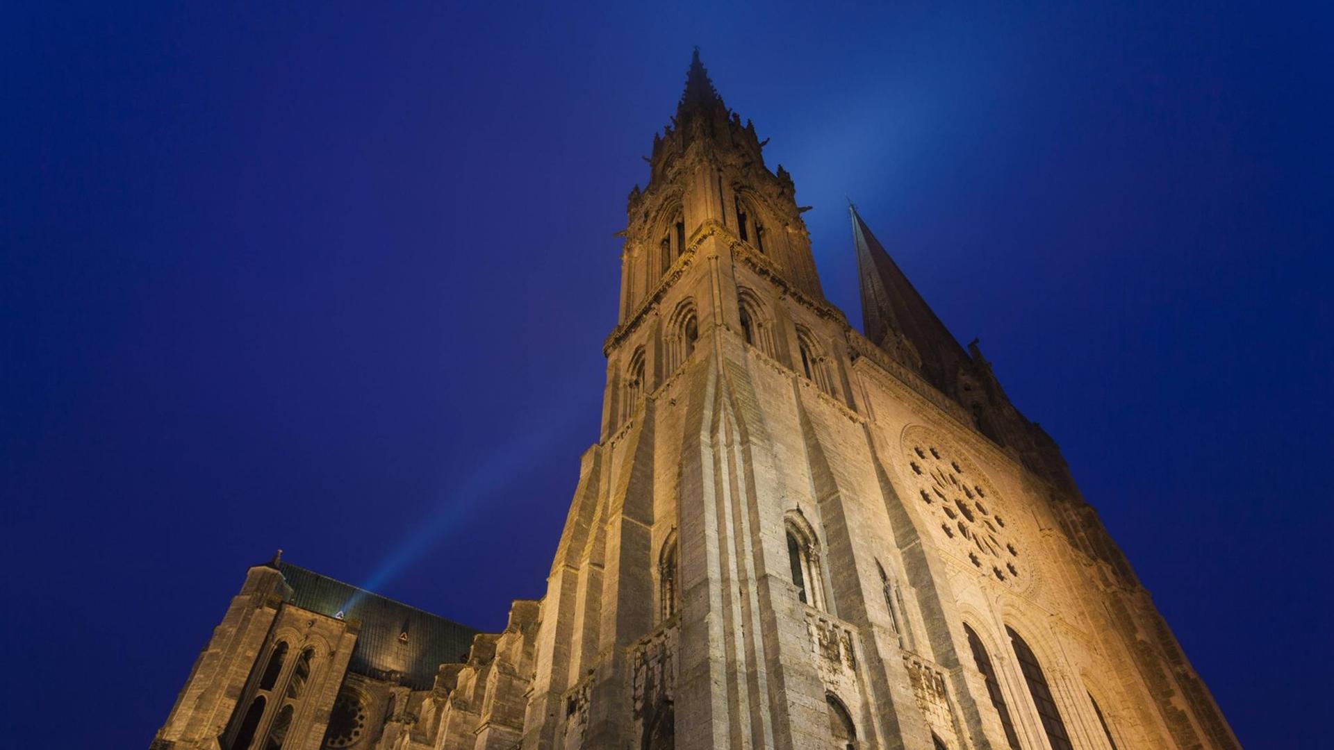 Die Kathedrale von Chartres in der Normandie in Frankreich – von Scheinwerfern bestrahlt, dahinter der Nachthimmel