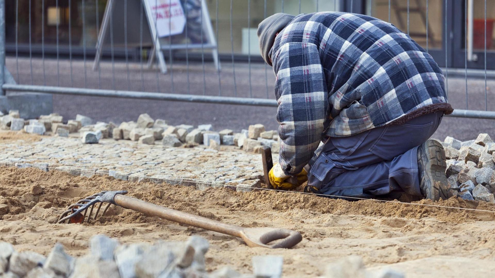 Bauarbeiter beim Verlegen von Kleinsteinpflaster in Berlin.