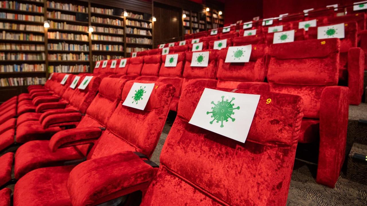 Einzelne Sitzplätze in einem Kinosaal vom Kino Astor Grand Cinema sind mit Zetteln mit aufgedrucktem angedeuteten Virus-Symbol abgesperrt, damit Kino-Besucher einen Abstand von 1,5 Meter zueinander einhalten können. 