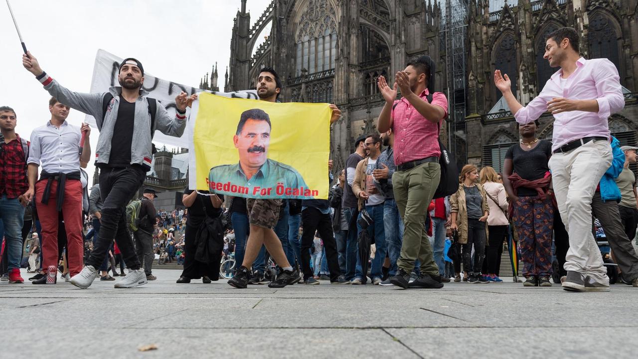  Kurden tanzen am 31.07.2016 am Hauptbahnhof in Köln (Nordrhein-Westfalen) mit einer Öcalan Fahne.