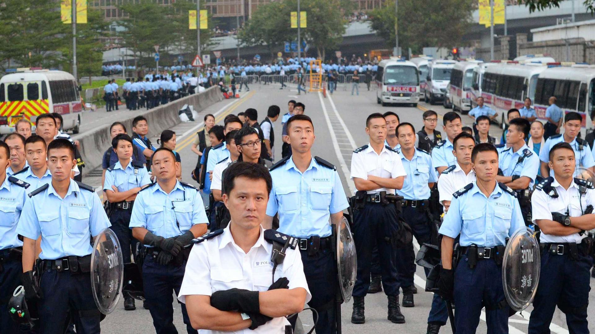 Auf einer Straße haben sich in mehreren Reihen Polizisten aufgestellt.