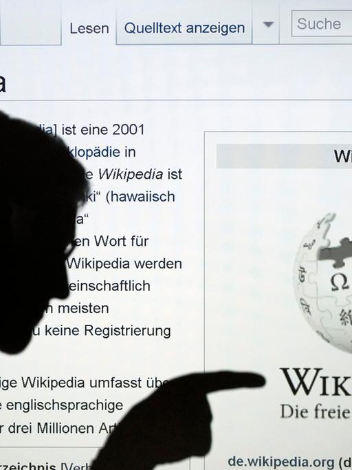 Die Silhouette eines Mannes, der mit seinem Finger auf das Wort Wikipedia