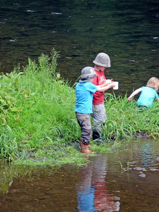 Drei Kinder stehen auf einer kleinen Grasinsel in der Wupper im Brückenpark unter der Müngstener Brücke in Solingen (Nordrhein-Westfalen). (Foto vom 25.05.2014)