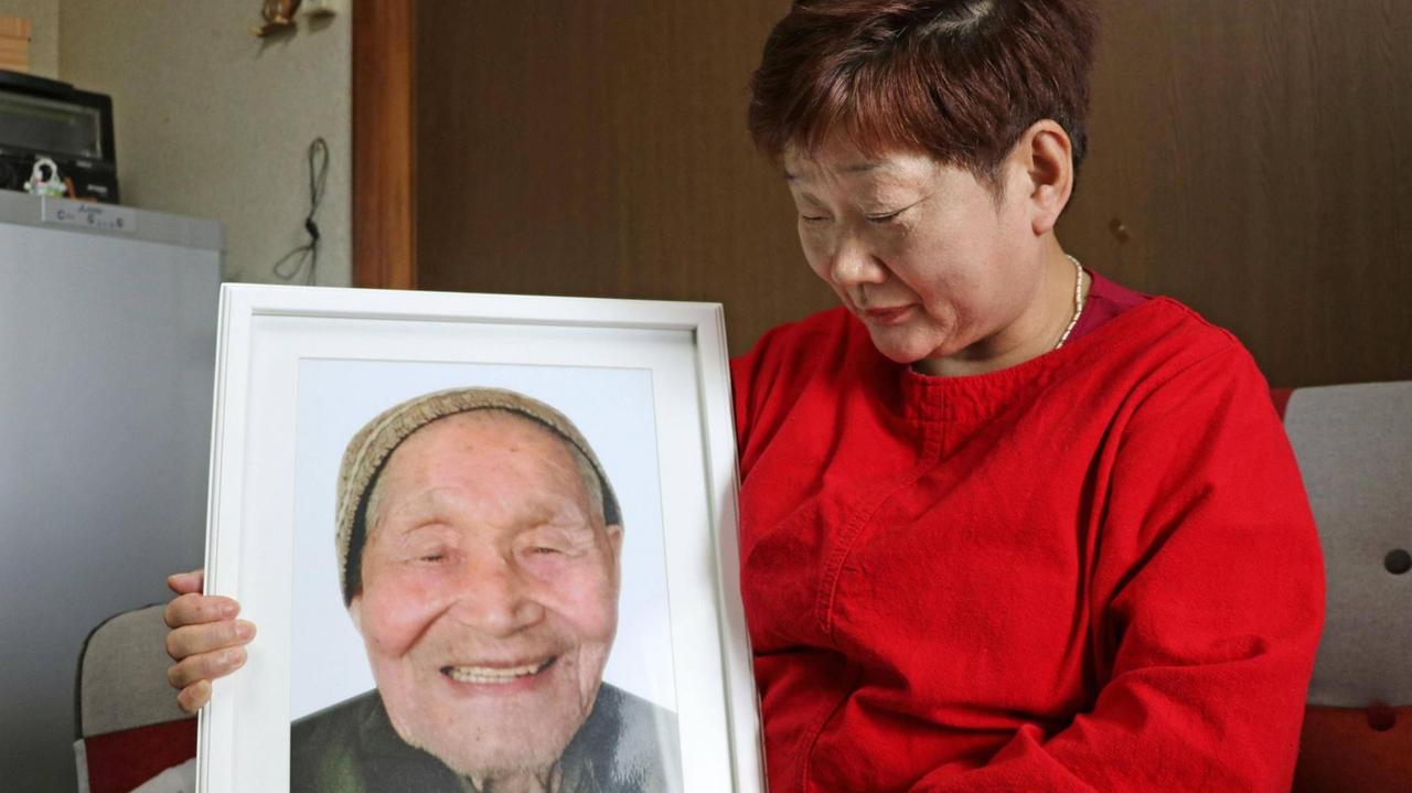 Mieko Okubo hält ein Foto ihres Schwiegervaters Fumio Okubo in die Kamera - der 102-Jährige hatte im April 2011 angesichts einer Evakuierungs-Anordnung Suizid verübt.