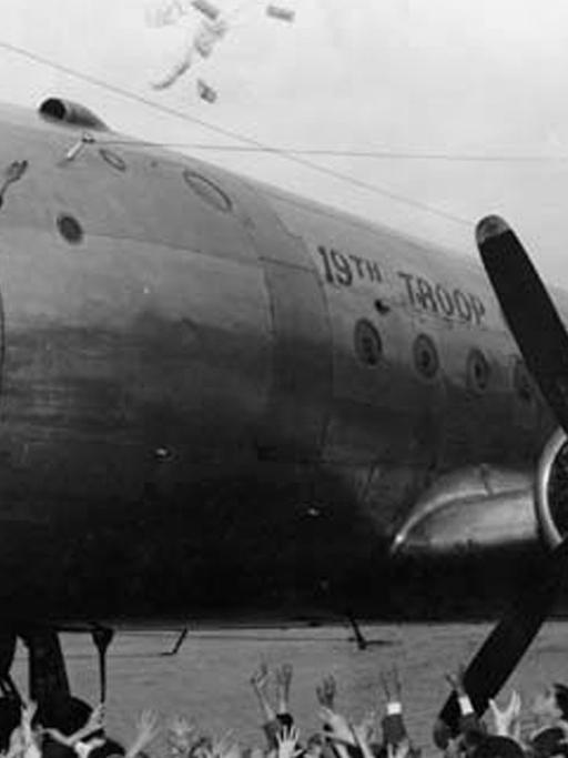 Pilot Gail S. Halvorsen wirft 1948 auf dem Flughafen Berlin-Tempelhof amerikanische Süßigkeiten aus seinem C-54 Transportflugzeug, die von Kindern auf dem Flugfeld aufgefangen werden. Der heute 85-jährige Halvorsen war 1948 während der Berlin-Blockade in einem so genannten Rosinenbomber im Einsatz.