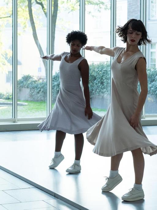 Zwei Tänzerinnen in weißen Kleidern zeigen in der Kunstsammlung Düsseldorf das Tanzstück "Fase, Four Movements to the Music of Steve Reich" von Anne Teresa De Keersmaeker