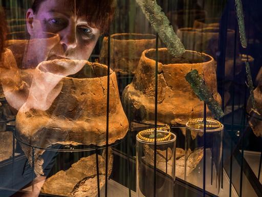 Museumsleiterin Heike Pilz schaut in eine Vitrine mit Grabausstattungen aus der Zeit zwischen 1300 - 1100 v. Chr., die am 04.10.2017 in der neuen Ausstellung "Blutiges Gold - Macht und Gewalt in der Bronzezeit" im Museumsgebäude des Archäologischen Freilichtmuseums Groß Raden (Mecklenburg-Vorpommern) in der Nähe von Sternberg zu sehen sind.