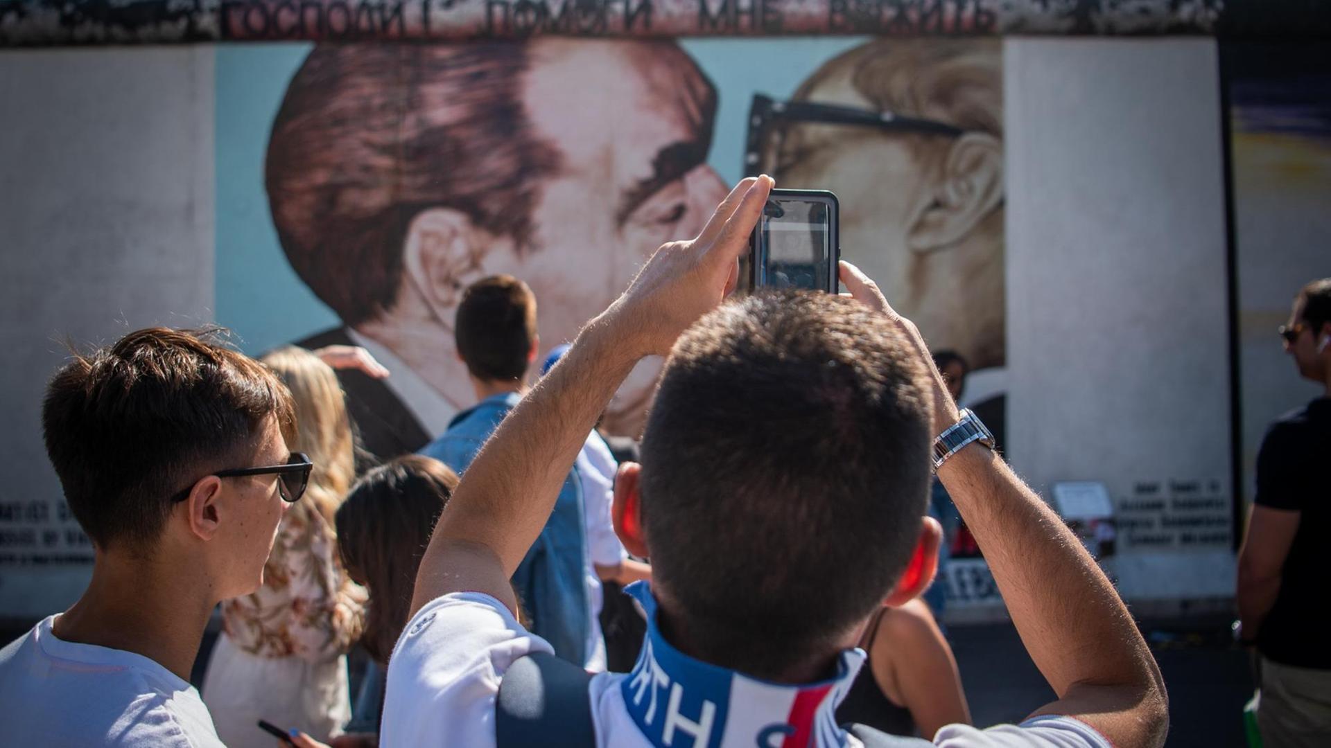Touristen und Besucher stehen vor dem sogenannten "Bruderkussgemälde" an der East Side Gallery. Vor fast 30 Jahren hatten sich hier Künstler verewigt und das längste noch erhaltene Teilstück der Berliner Mauer mit ihren Kunstwerken umgedeutet.
