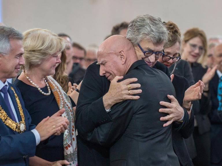 Sebastião Salgado umarmt seinen Laudator Wim Wenders. Daneben stehen Frankfurts Oberbürgermeister Peter Feldmann und Kulturstaatsministerin Monika Grütters.