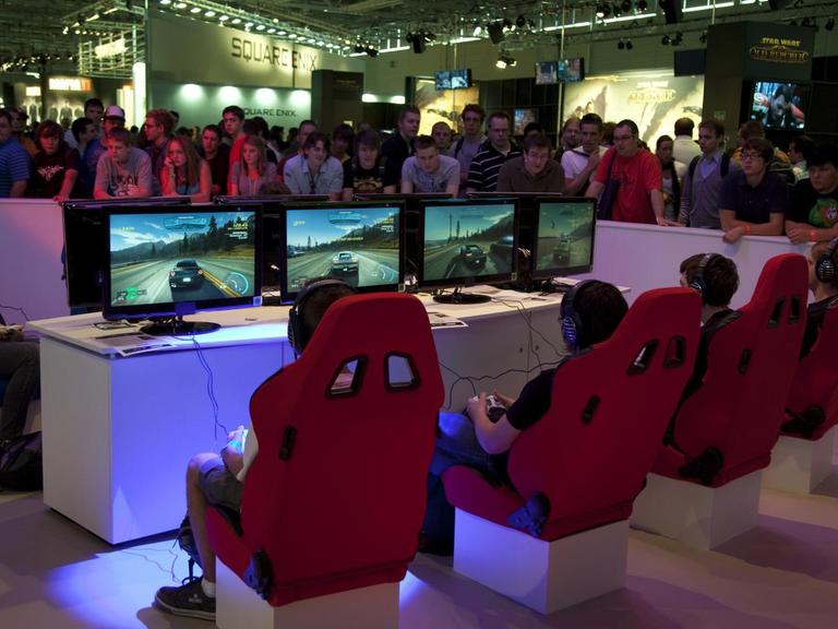 Auf der Gamescom-Messe für Computerspiele spielen Jugendliche das Autorennen 'Need for Speed'.