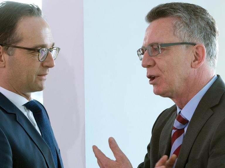 Bundesjustizminister Heiko Maas und Bundesinnenminister Thomas de Maiziere unterhalten sich auf einem Flur 