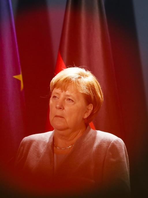 Das Rotlicht einer Fernsehkamera liegt auf Bundeskanzlerin Angela Merkel (CDU), die vor einer Deutschland- und einer EU-Flagge zu sehen ist.
