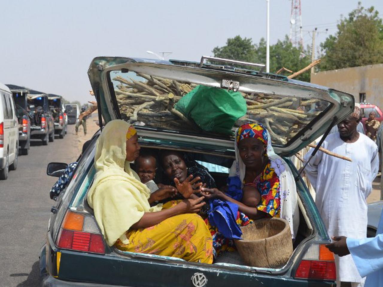 Women and children gather into a car's trunk as villagers flee the village of Jakana, outside Maiduguri, Borno State, Nigeria