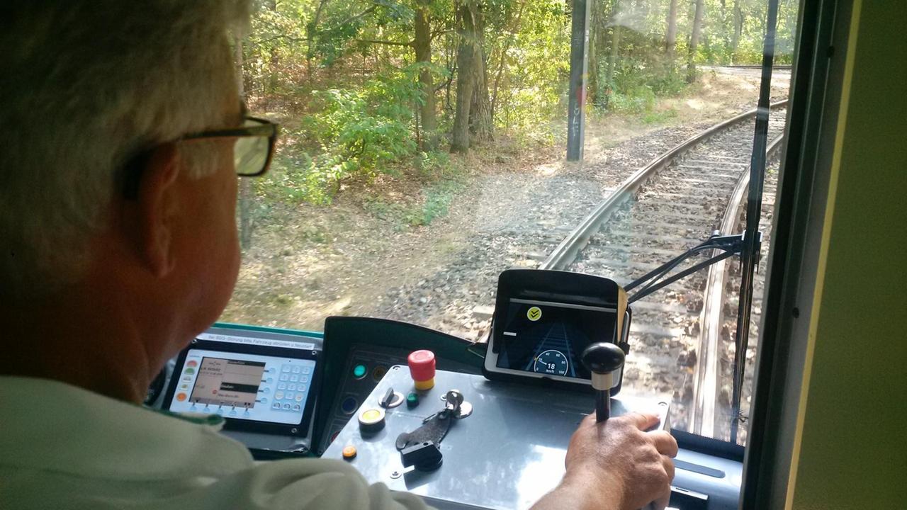 Ein Straßenbahnfahrer blickt durch die Frontscheibe auf die Schienen