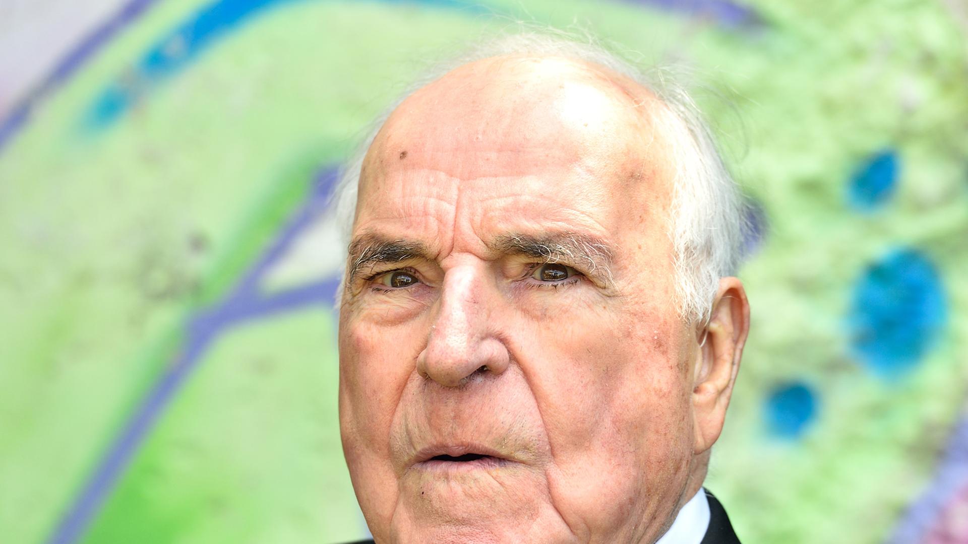 Der ehemalige Bundeskanzler Helmut Kohl (CDU) sitzt am 16.05.2014 in Oggersheim (Rheinland-Pfalz) im Garten seines Wohnhauses vor einem Originalstück der Berliner Mauer.
