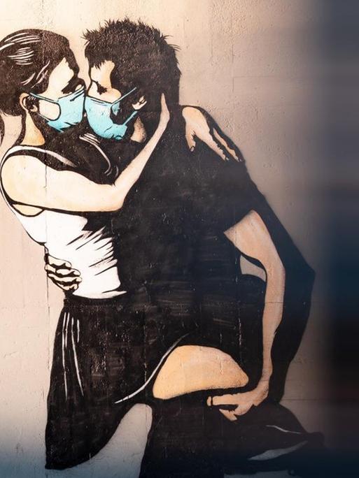 Street Art in Bryne, Norwegen. Auf einer Wand sieht man die Darstellung eines Pärchens, beide tragen medizinische Masken und sind im Begriff, sich zu küssen.