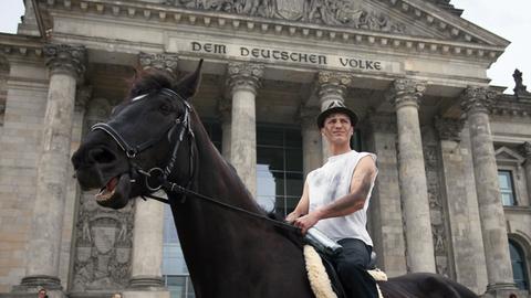 Der Berliner Künstler Bill van Bergen sitzt auf einem Pferd vor dem Reichstagsgebäude in Berlin.