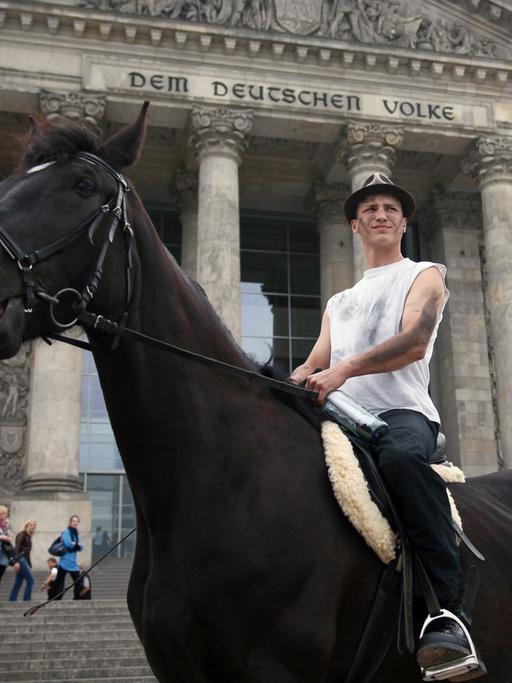Der Berliner Künstler Bill van Bergen sitzt auf einem Pferd vor dem Reichstagsgebäude in Berlin.
