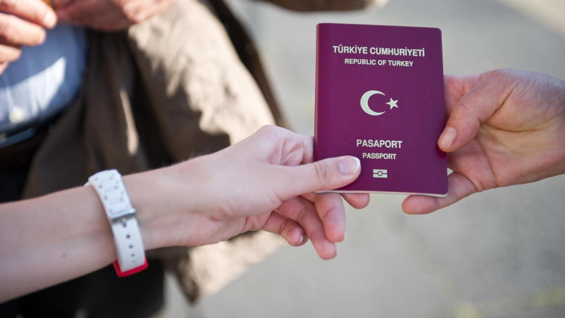 Eine türkische Wahlberechtigte zeigt am 03.08.2014 vor dem Olympiastadion in Berlin ihren türkischen Pass, um in das Wahlzentrum für die türkische Präsidentenwahl in Deutschland zu gelangen.