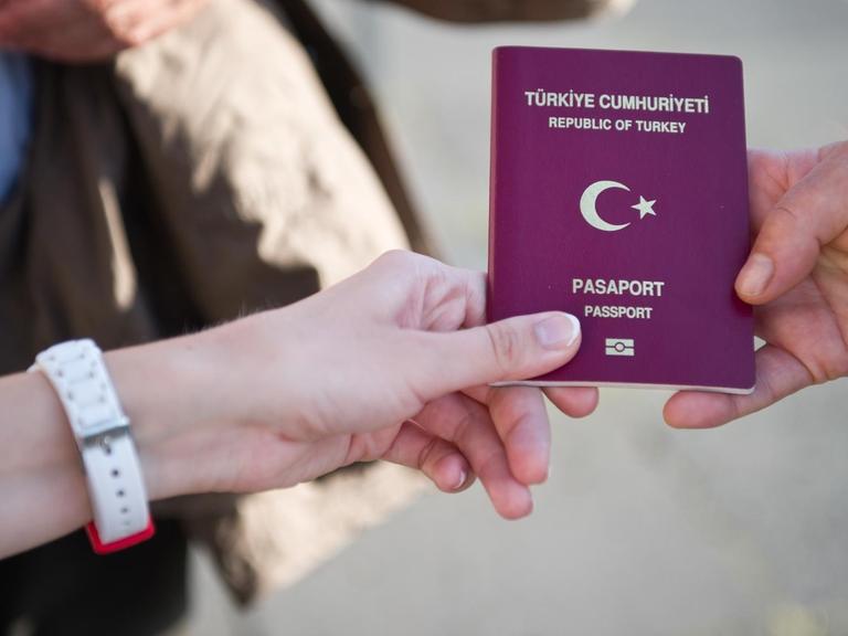 Eine türkische Wahlberechtigte zeigt am 03.08.2014 vor dem Olympiastadion in Berlin ihren türkischen Pass, um in das Wahlzentrum für die türkische Präsidentenwahl in Deutschland zu gelangen.