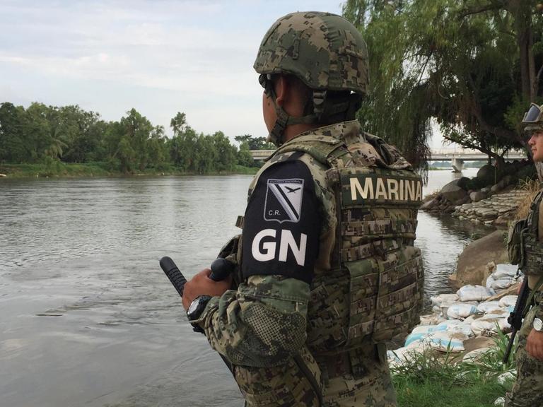 Bewaffnete Grenzpolizisten bewachen einen Fluss.