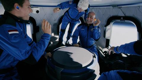 Drei Personen, teilweise schwebend, in einer Raumkapsel