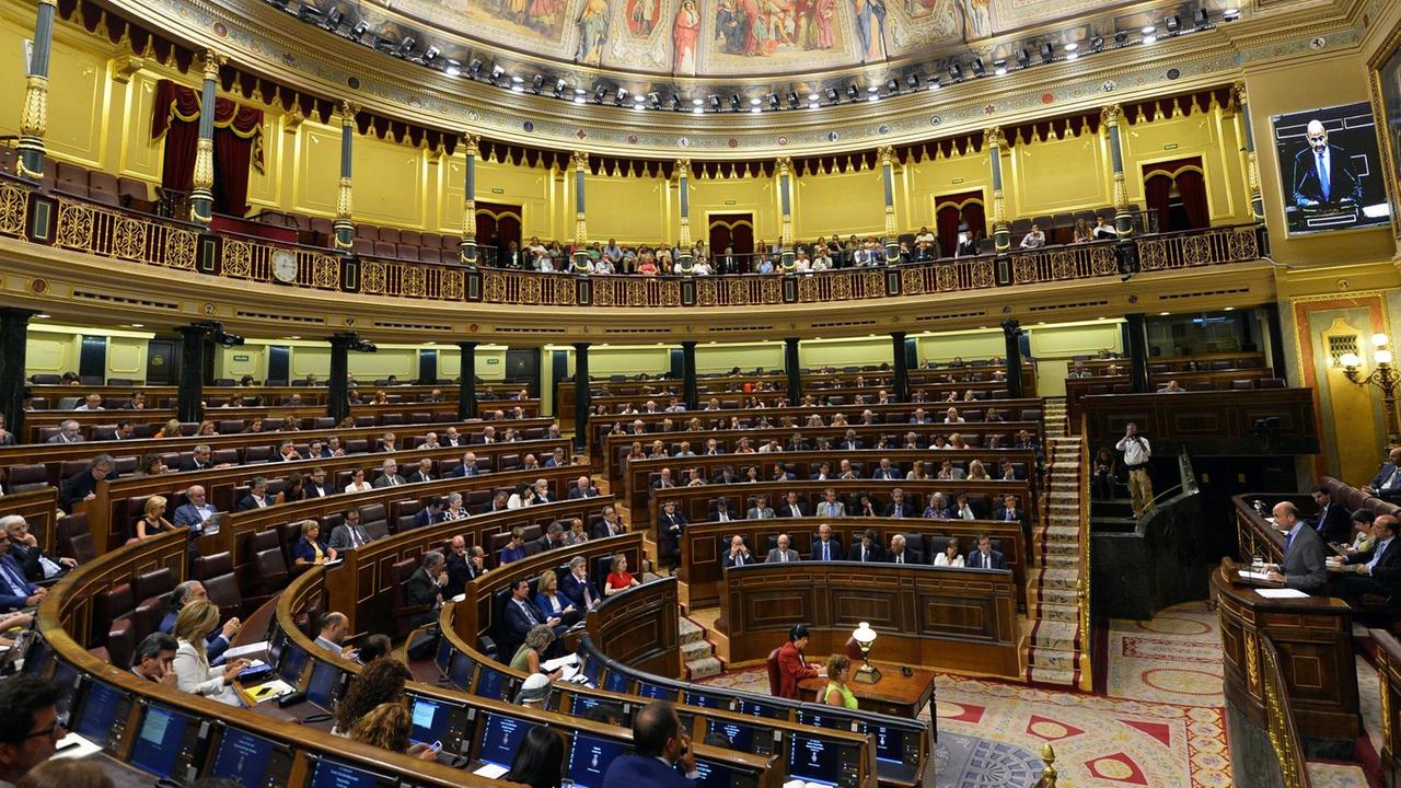 Das vollbesetzte Parlament in Madrid. Am Rednerpult steht der spanische Wirtschaftsminister Luis de Guindos und spricht zu den Abgeordneten.
