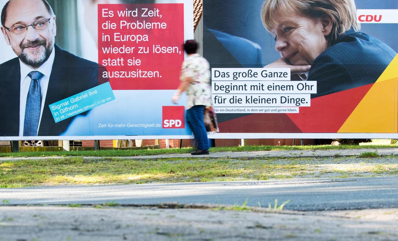 Eine Fußgängerin läuft in Müden (Aller) (Niedersachsen) vorbei an Wahlplakaten von SPD-Kanzlerkandidat Martin Schulz und CDU-Spitzenkandidatin und Bundeskanzlerin Angela Merkel