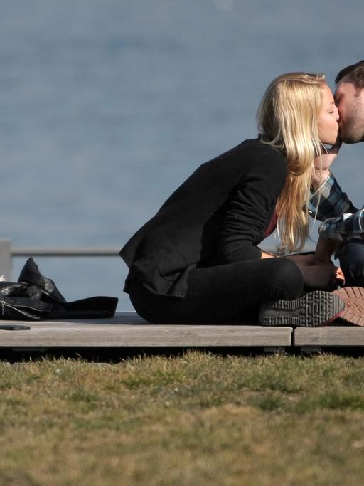 Ein verliebtes Paar genießt in Mainz am Rheinufer das sonnige Wetter und küssen sich auf der Uferpromenade.