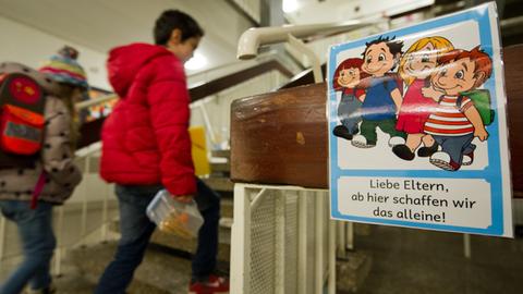 An einer Grundschule in Stuttgart laufen Schüler an einem Schild vorbei, das überfürsorgliche Eltern ermahnt, ihre Kinder alleine weitergehen zu lassen.