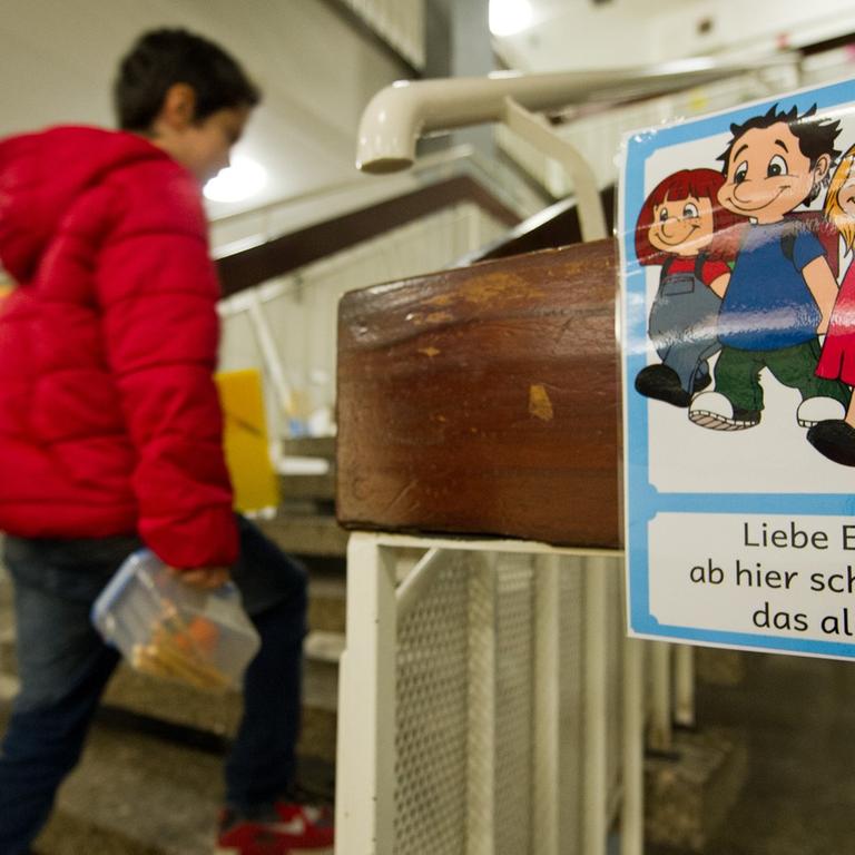 An einer Grundschule in Stuttgart laufen Schüler an einem Schild vorbei, das überfürsorgliche Eltern ermahnt, ihre Kinder alleine weitergehen zu lassen.