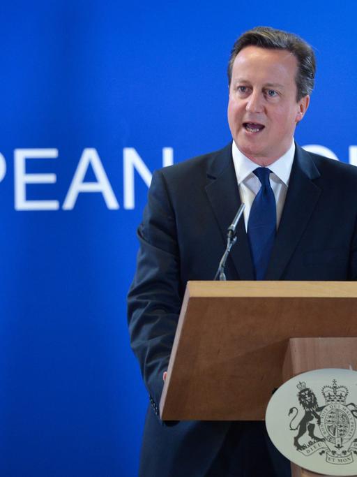 David Cameron spricht an einem Rednerpult, im Hintergrund die britische Flagge Union Jack