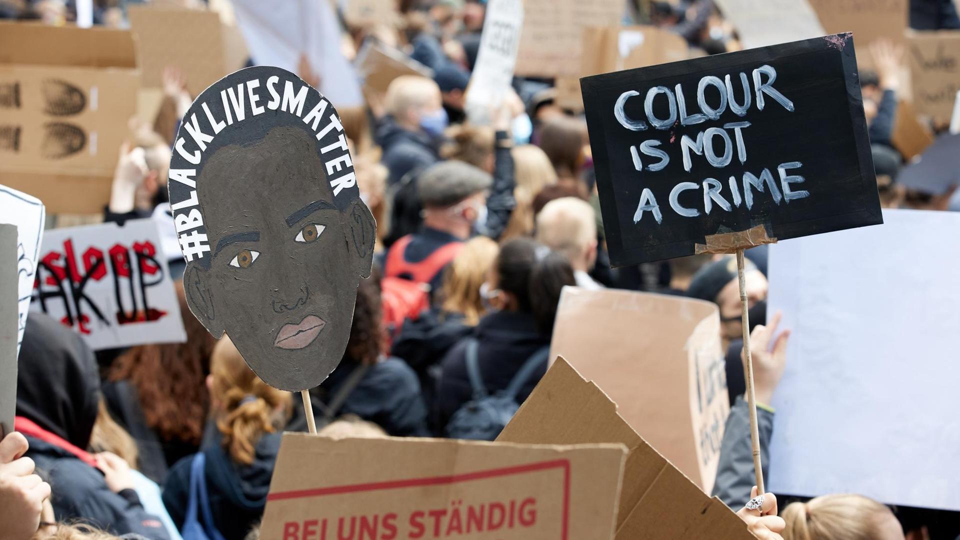Teilnehmer von einer Demonstration in Hamburg halten Plakate in die Höhe.