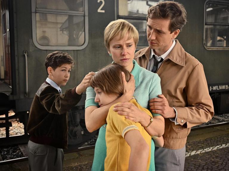 Eine Familie steht vor einem Zug und es sieht so aus, als würden die Personen sich voneinander verabschieden.