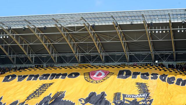 Fans von Dynamo Dresden ziehen ihre Blockfahne hoch.