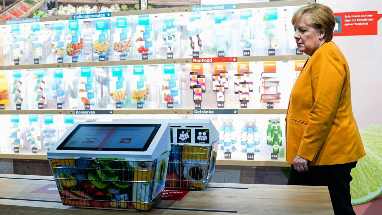 Bundeskanzlerin Angela Merkel geht bei einer Führung zur Eröffnung der Klima Arena in Sinsheim,Baden-Württemberg durch ein Modell eines Supermarktes.