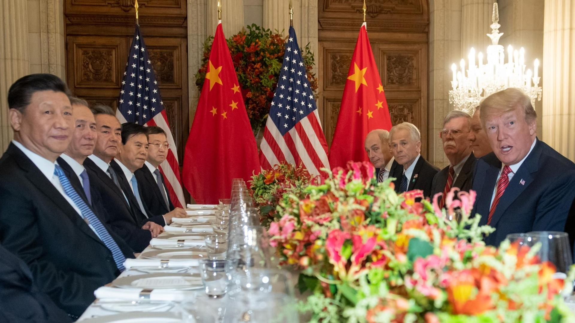 Xi Jinping (l.) und Trump sitzen sich mit ihren Delegationen an einem großen Tisch gegenüber.