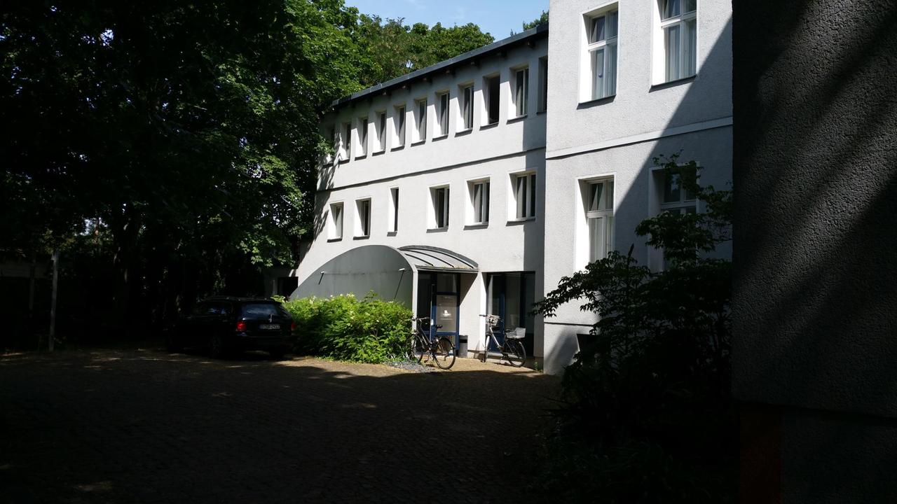 Eine weiße Remise im grünen Hinterhof des Berliner Bezirks Pankow.