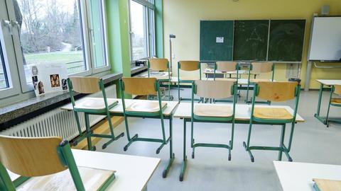 Klassenzimmer einer Schule mit einer Tafel und hochgestellten Stühlen