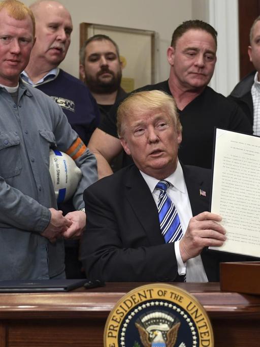 Das Bild zeigt US-Präsident Trump nach der Unterzeichnung seiner Verordnung über Schutzzölle. Er ist umringt von amerikanischen Stahlarbeitern.