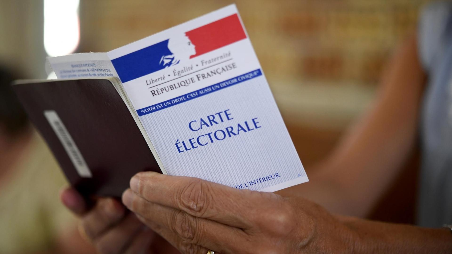 Eine Frau hält eine Wahlkarte an einem Wahllokal in Carhaix-Plouguer in Westfrankreich während der zweiten Runde der Parlamentswahl.