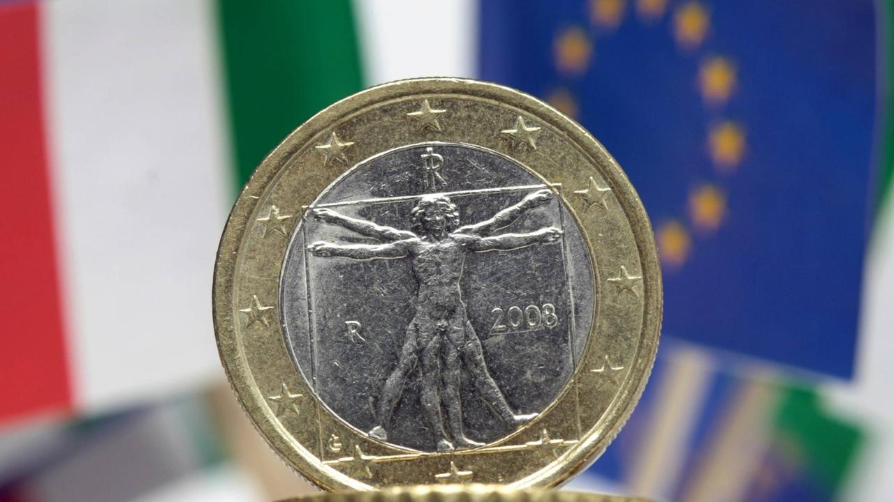 Das Symbolfoto zeigt Flaggen aus Italien und der EU, zusammen mit einer Euro Geldmünze aus Italien.