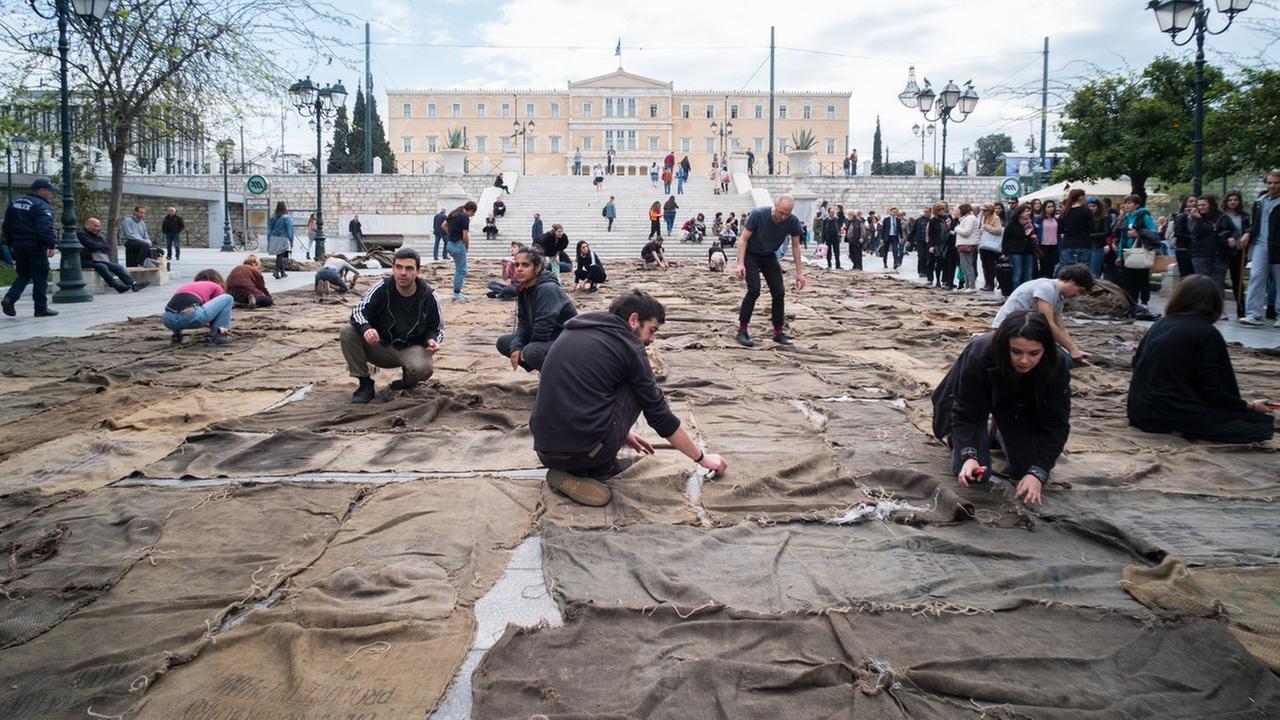 Helfer nähen auf dem Syntagma-Platz unzählige gebrauchte Jutesäcke zu einem Teppich zusammen