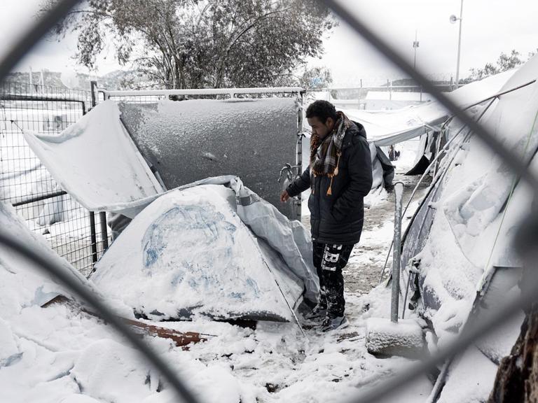 Ein Mann steht vor einem eingeschneiten Iglu-Zelt.