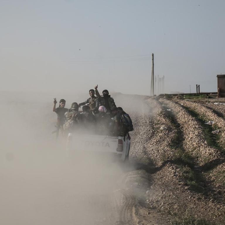Soldaten der türkisch unterstützten syrischen Nationalarmee gestikulieren nach Zusammenstößen mit kurdischen Kämpfern. Ihr Fahrzeug hinterlässt eine Staubwolke 