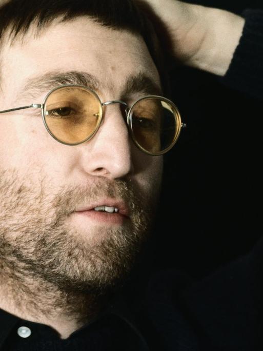 Farbfoto von John Lennon mit Brille mit gelben Gläsern.