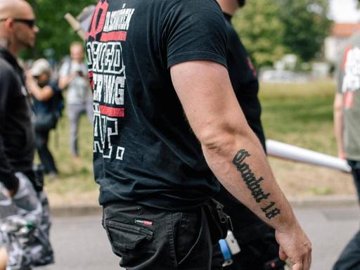 Ein schwarz gekleideter Mann mit einem "Combat 18"-Tattoo am Unterarm läuft neben anderen Männern am 20.07.19 bei einer Demonstration von "Die Rechte" in Kassel