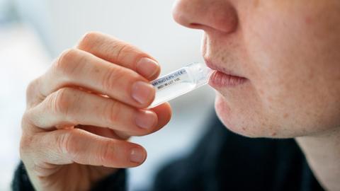 Jemand führt einen Selbsttest mittels Gurgelmethode durch